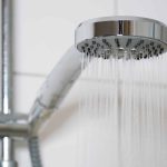 shower with modern showerhead and running water in domestic bathroom close-up